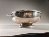 a silver bowl with a handle on a table