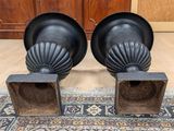 pair of black cast iron urns on a rug in front of a wooden cabinet