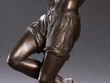 bronze statue of a man holding a tennis racquet on a base