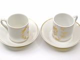 two cups and saucers sitting on a white table