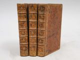 two old books are stacked on top of each other on a white surface