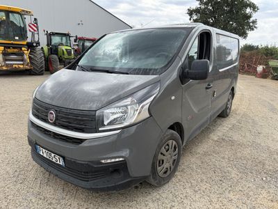 a grey van parked in front of a building with a tractor behind it