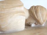 a statue of a woman laying down on a marble block