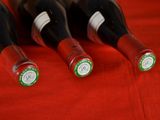 four bottles of wine are lined up on a red cloth