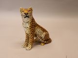 une figurine représentant un guépard assis sur une surface blanche