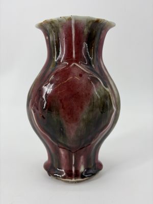 un petit vase posé sur une surface blanche