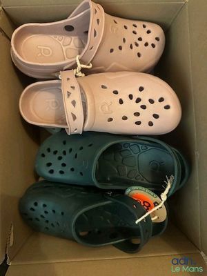 several pairs of crocs are in a cardboard box on the floor