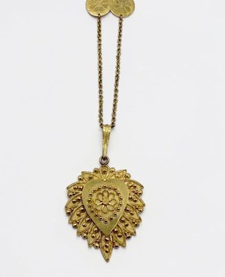 un collier en or avec un médaillon en forme de cœur suspendu à une chaîne