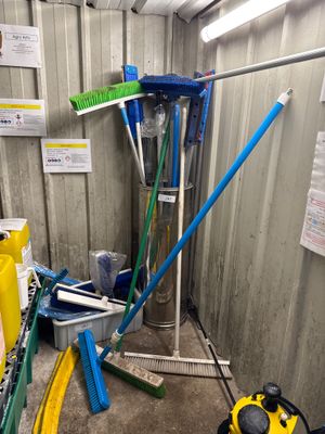 un tas de balais et d'outils dans un coin de la pièce
