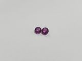 a pair of purple sapphires sitting on top of a white surface