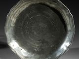 une assiette en argent posée sur une table, sur fond noir