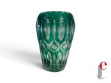 une image représentant un vase en verre vert posé sur une surface blanche