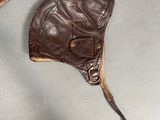 a brown leather hat and a brown leather glove on a table