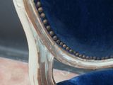 the back of a chair with a blue velvet upholstered seat