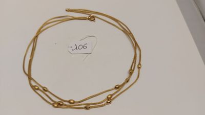 gros plan d'un collier en or sur une surface blanche
