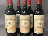 quatre bouteilles de vin rouge sont alignées sur une table
