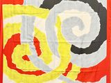 a red, yellow, black, and white scarf hanging on a wall