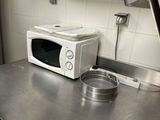 un micro-ondes posé sur un plan de travail en métal dans une cuisine