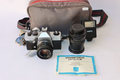 un appareil photo et d'autres objets posés sur une table, à côté d'un sac