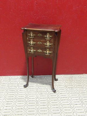 une petite table en bois avec un tiroir, posée devant un mur rouge