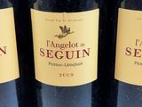 three bottles of red wine are lined up on a table