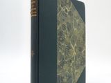 an old book sitting on top of a white table next to a white wall