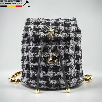 un sac à dos en tweed noir et blanc avec des finitions dorées