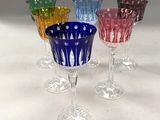 quatre verres à vin de couleurs différentes posés sur une table blanche