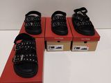 trois paires de chaussures noires à semelles cloutées posées sur une boîte