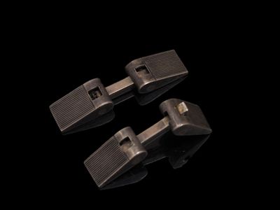 trois clips métalliques sur une surface noire, avec un fond noir