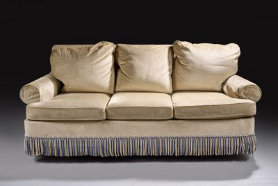 an image of a beige couch with pillows on it in a dark room