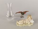 deux figurines représentant un bébé et un oiseau, posées à côté d'un vase