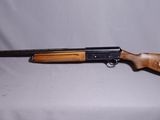 un fusil posé sur une table devant un fond blanc