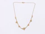 a gold necklace with a flower design on a chain