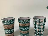 three cups and a pitcher sitting next to each other on a table