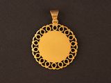 a gold plated pendant with a circular design on a black background