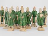 ensemble de figurines sculptées représentant des hommes vêtus de manteaux verts et coiffés de chapeaux