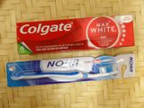 two toothbrushes on the table next to a box of toothpaste