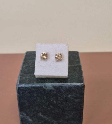 des boucles d'oreilles à clous plaquées or posées sur un bloc de marbre posé sur une table