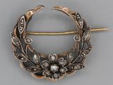 a silver brooch with a flower and leaves on it