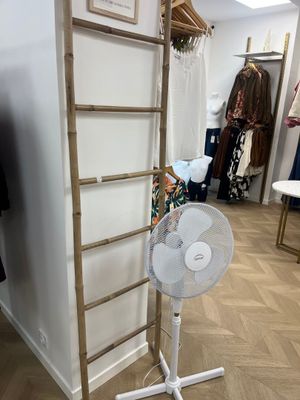 wooden ladder leaning against a wall with a fan in front of it