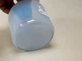 a person holding a bottle of blue liquid on a table
