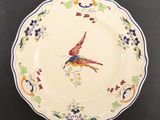 a plate with a bird painted on it sitting on a table