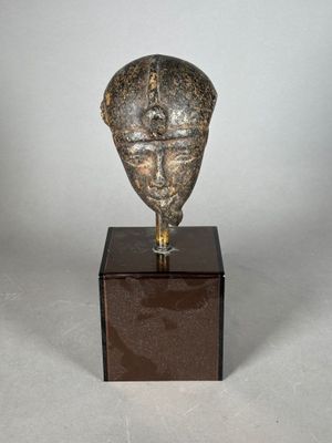 statue représentant la tête d'un homme, posée sur un socle en bois
