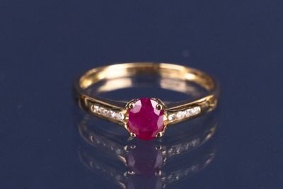 gros plan d'une bague en or avec un rubis et des diamants