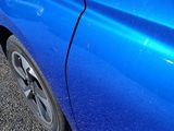 a close up of a blue car parked on the side of the road