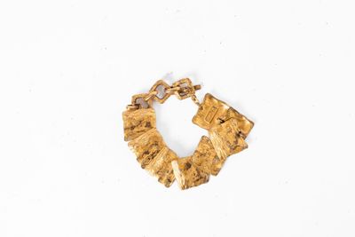 Le bracelet en or est fabriqué à partir d'un morceau de bois et comporte une chaîne qui y est attachée.
