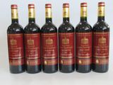 six bottles of red wine lined up in a row on a white surface
