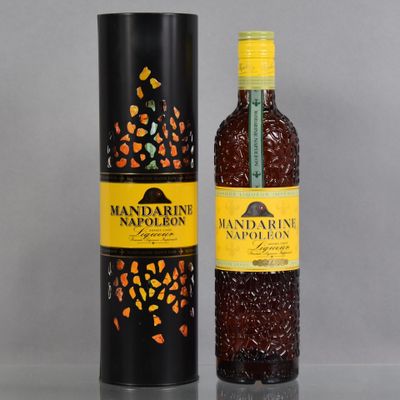 La bouteille se trouve à côté de la boîte noire sur la table.