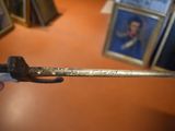 a hand holding a sword with a picture of a man on it